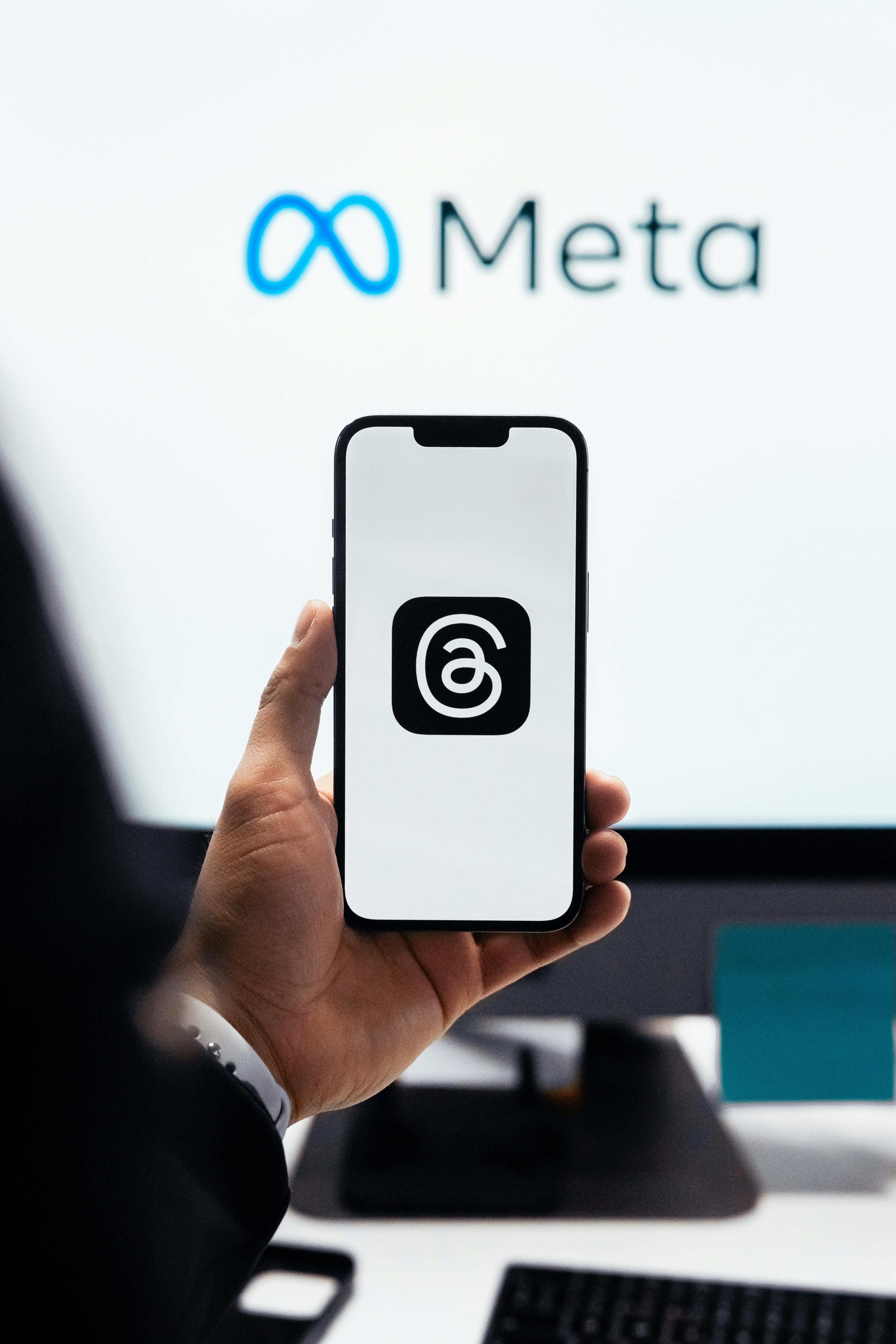 close up of a man holding a smartphone displaying the logo of the threads app