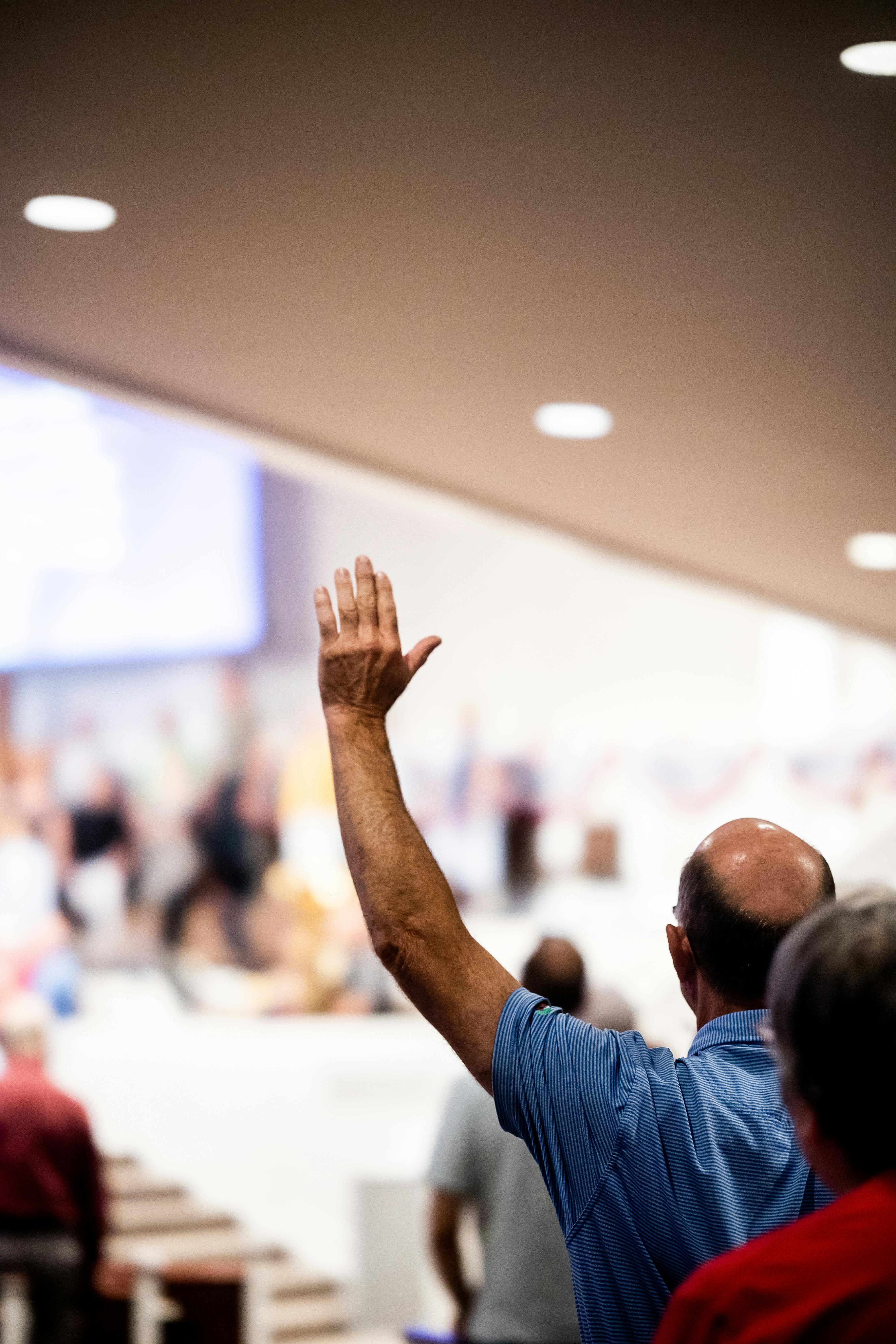 man raising hand at gathering