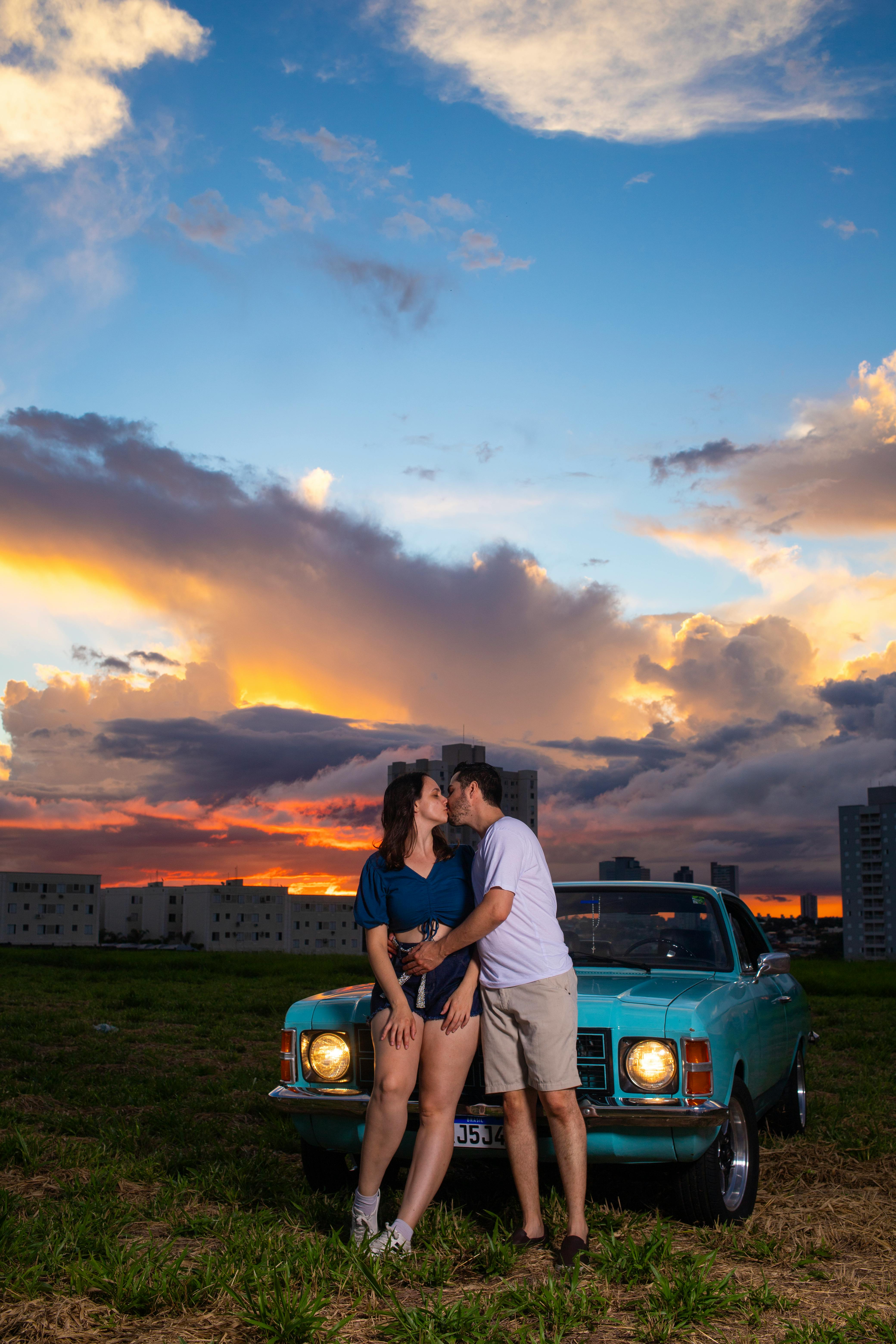romantic couple by vintage car at sunset