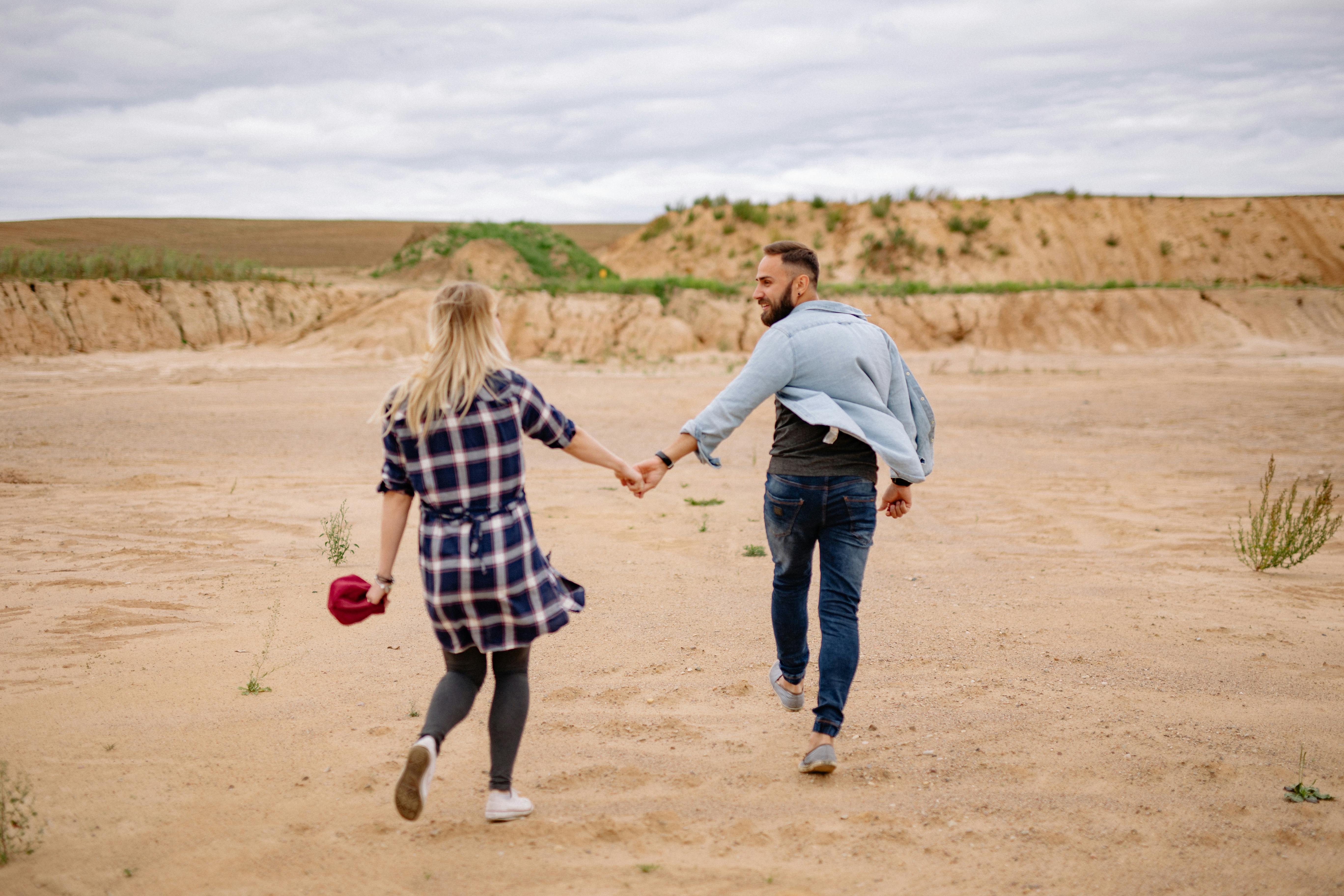 couple holding hands and walking on beach