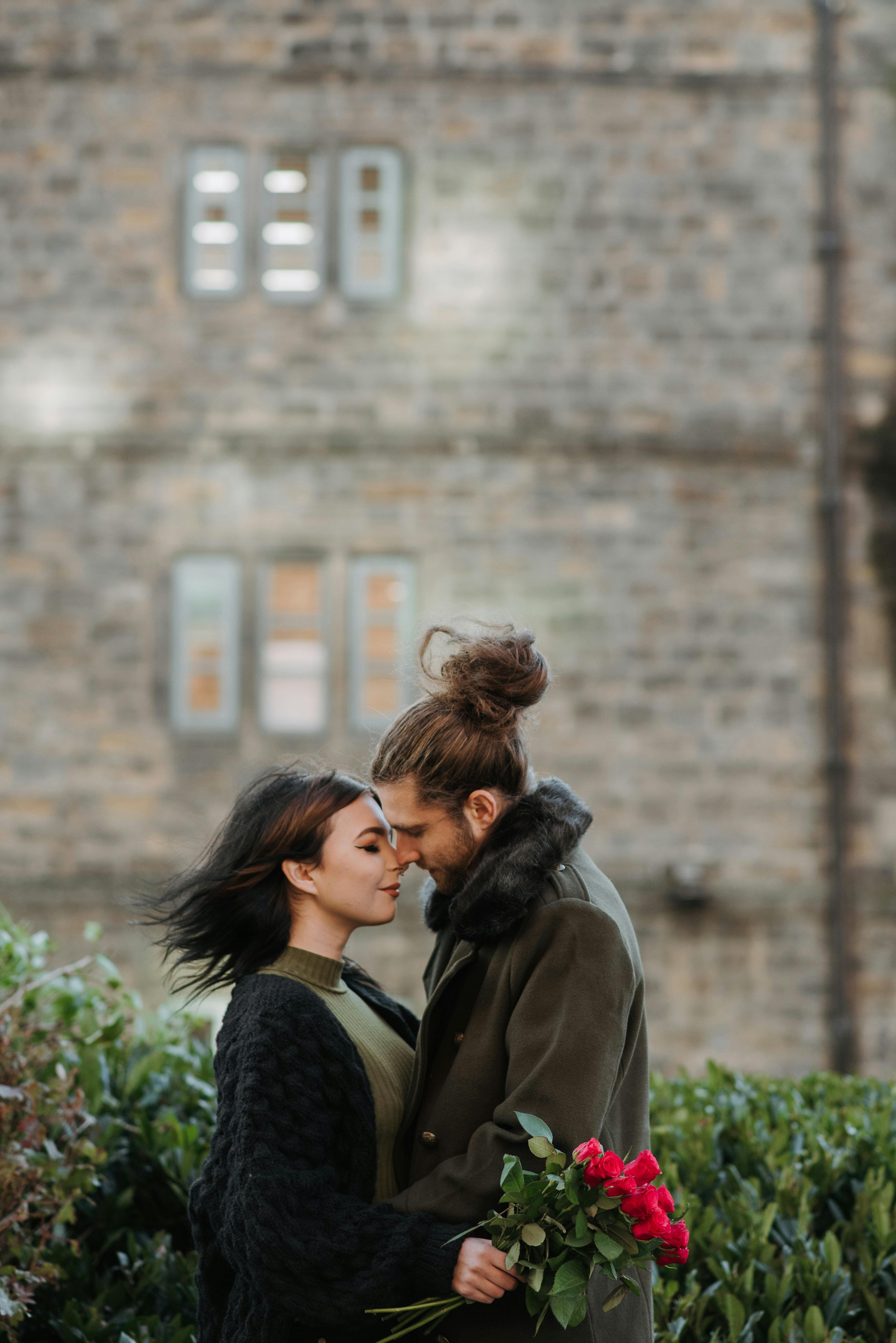 couple touching noses while embracing on city street