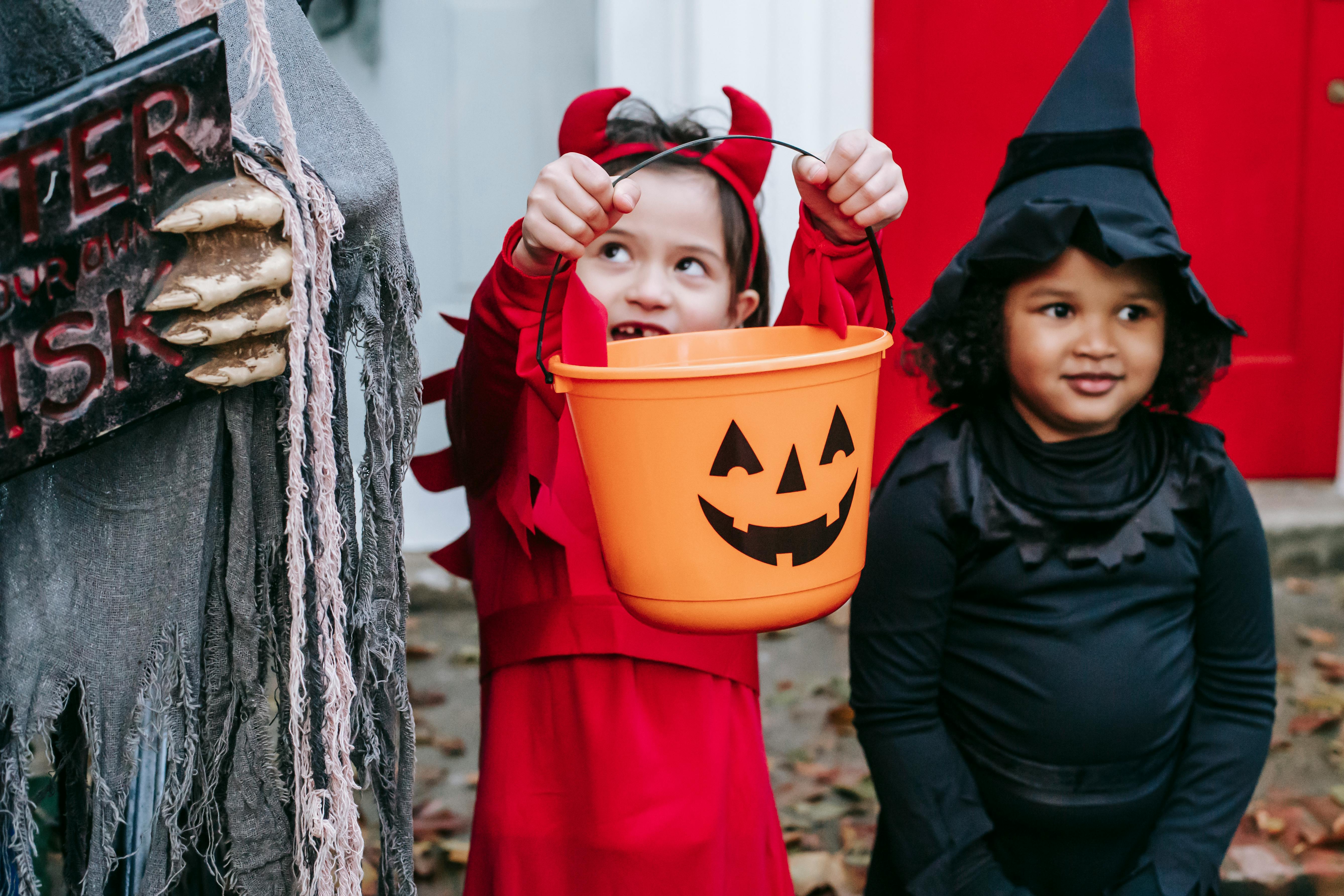 multiracial kids in halloween costumes near decorations