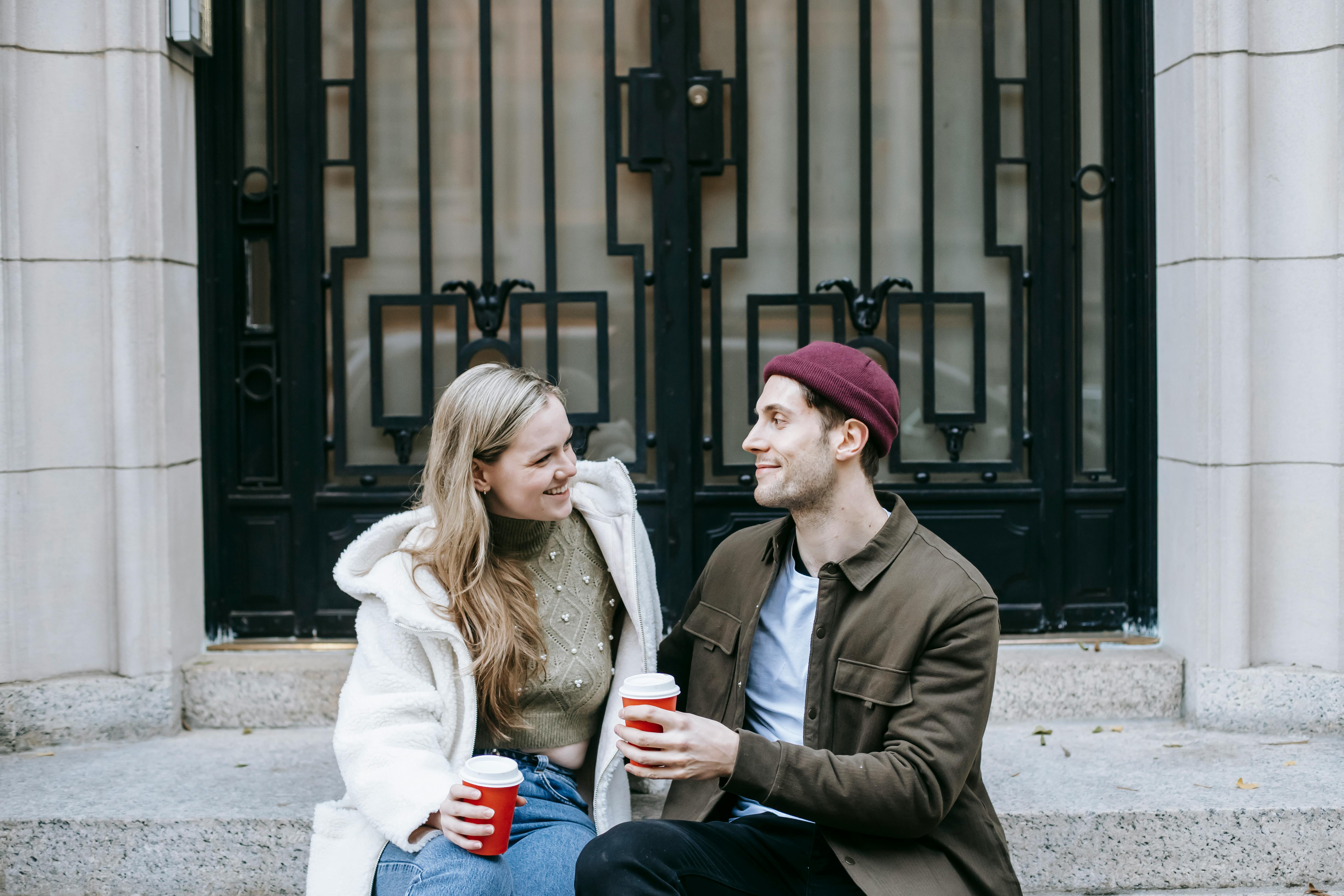 happy man and woman drinking hot tea and speaking on street