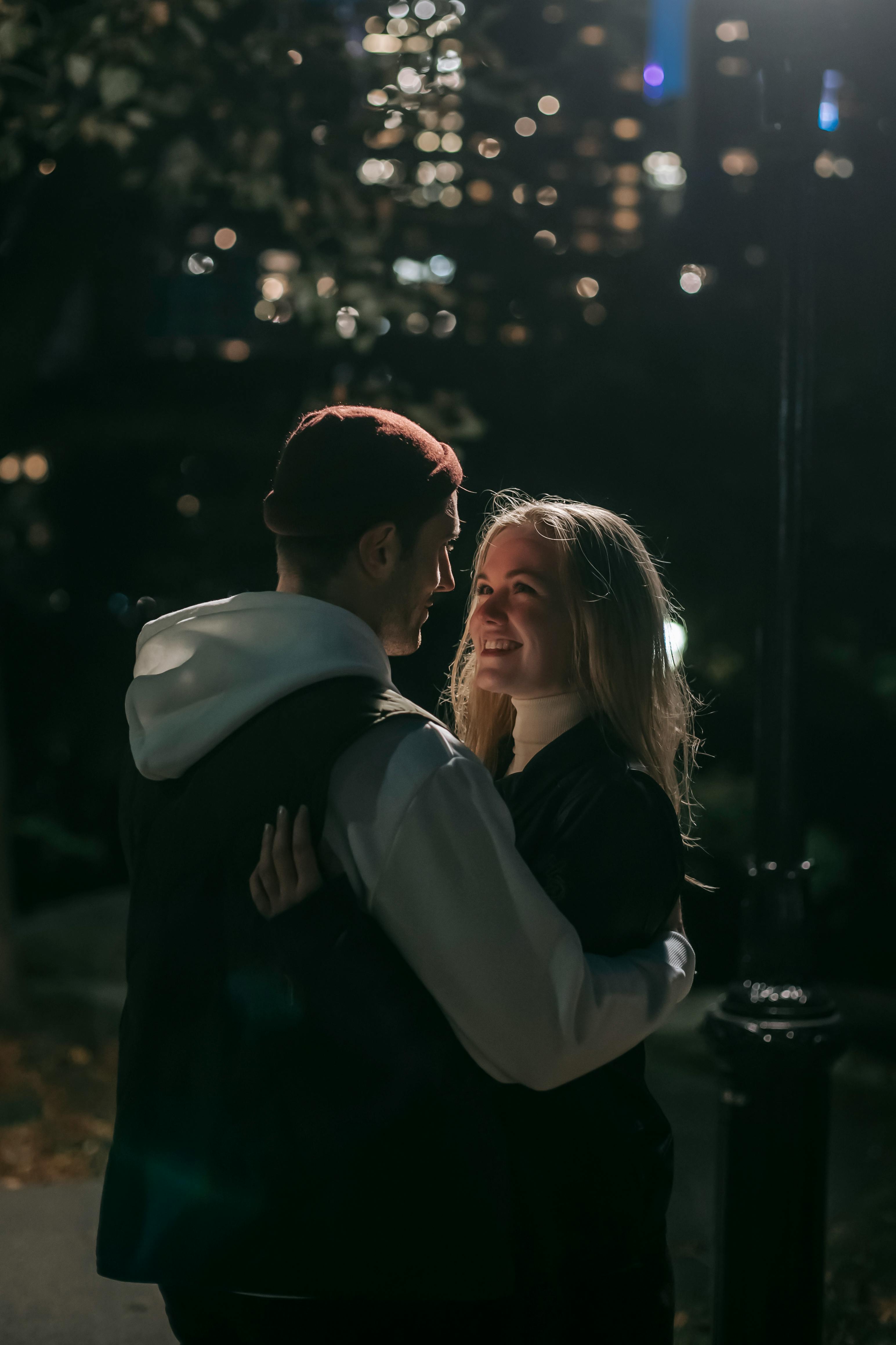 cheerful couple hugging in park in darkness