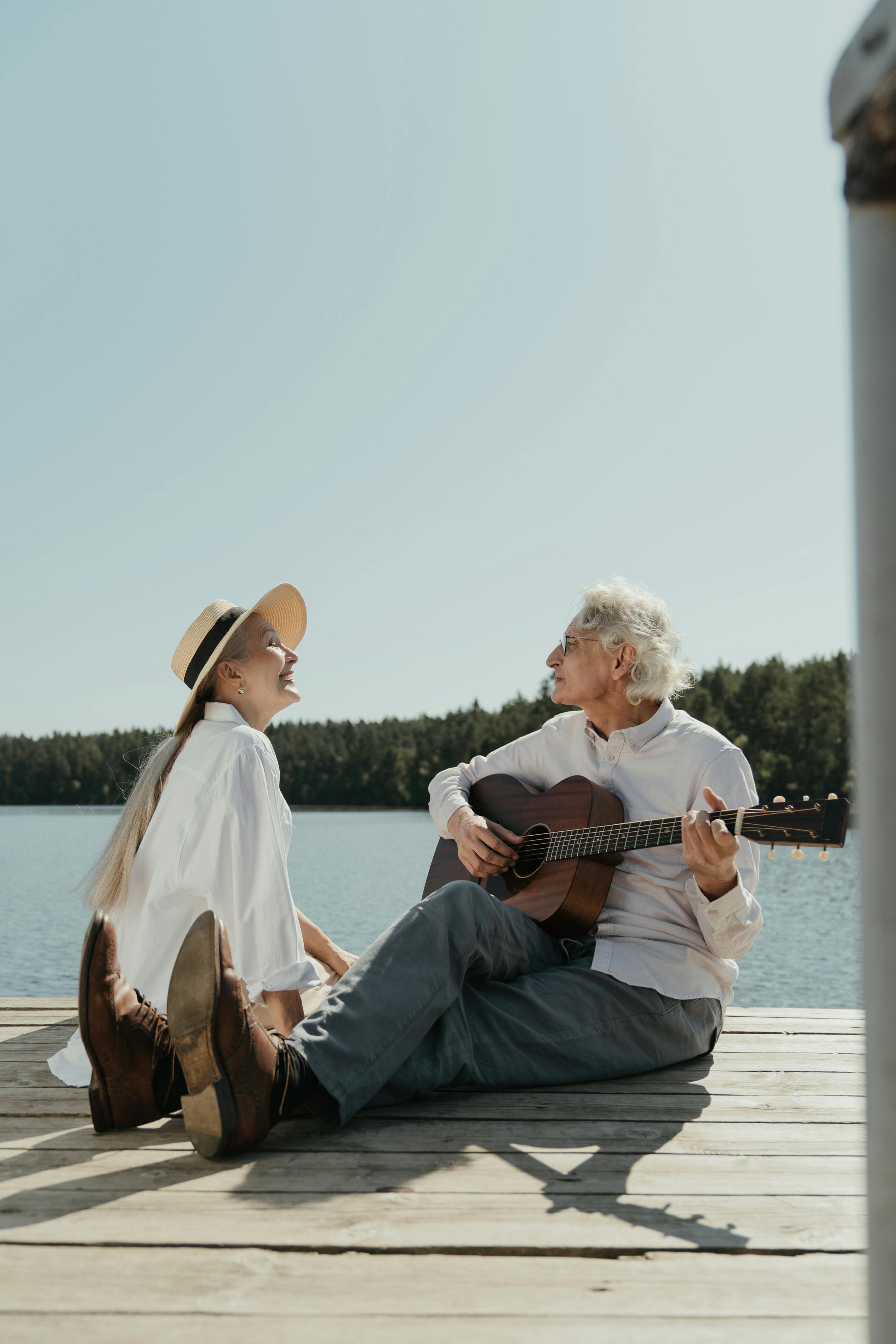 man in white dress shirt playing guitar sitting on white wooden bench