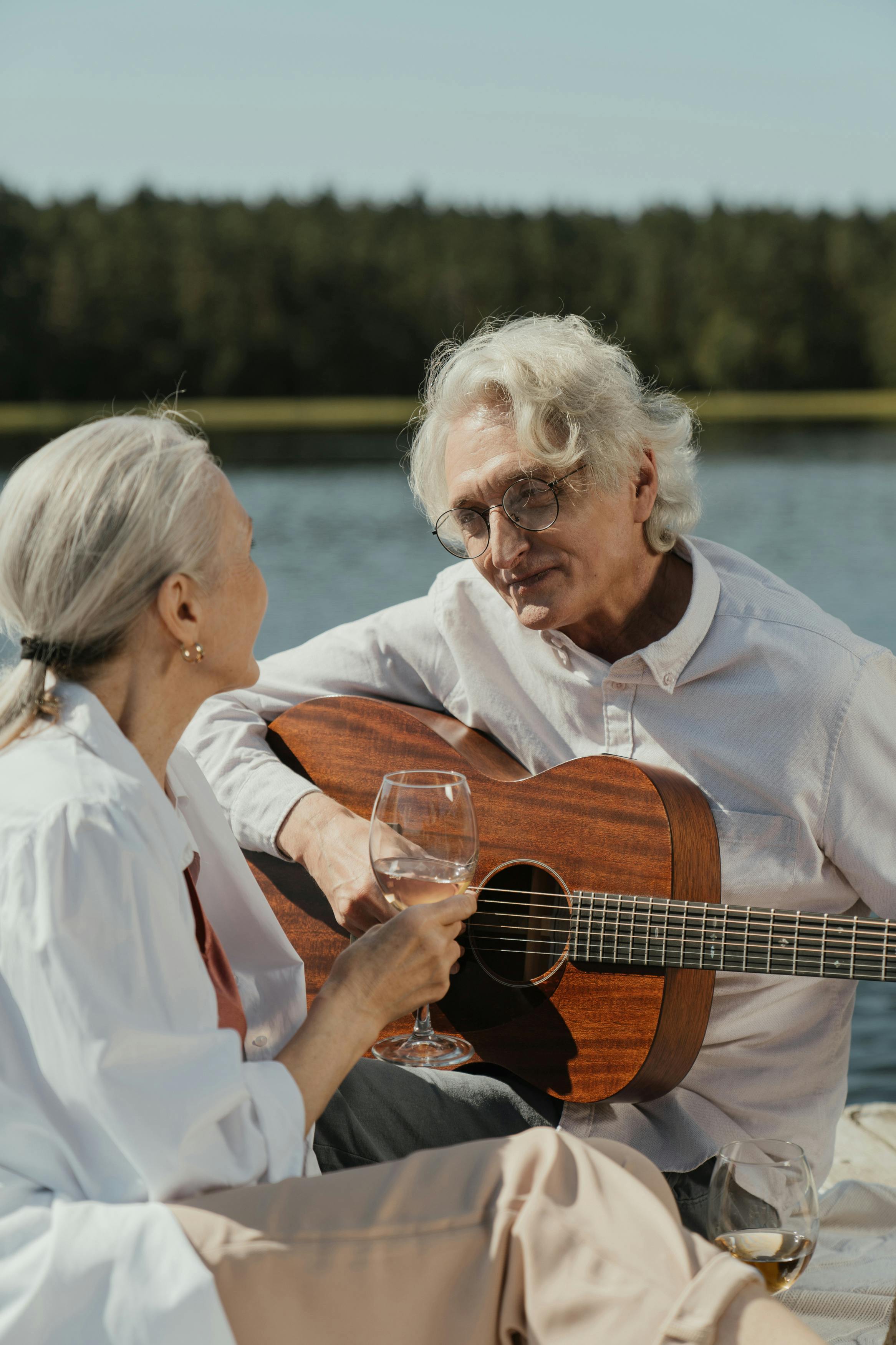 man in white button up shirt holding brown acoustic guitar