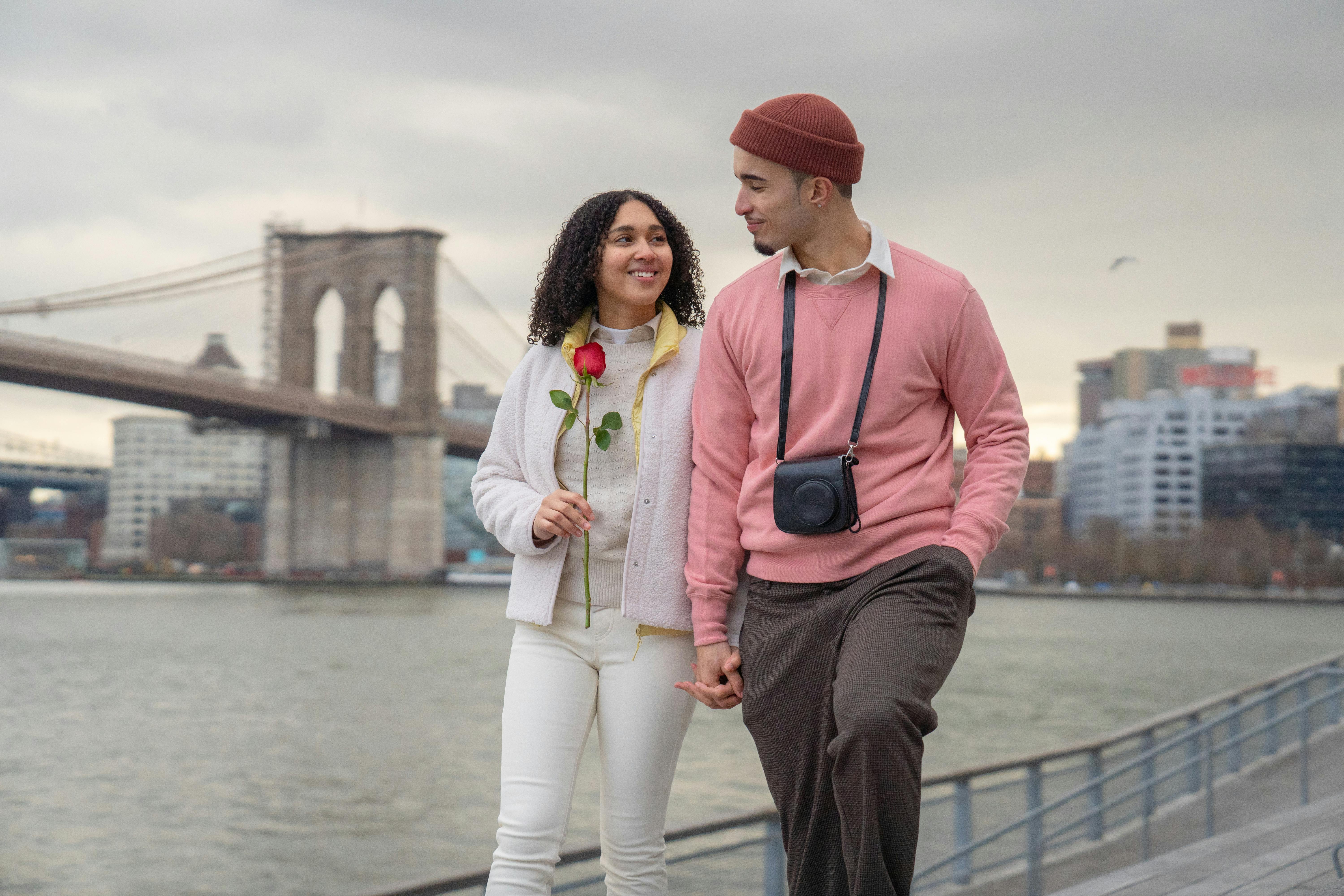 cheerful hispanic couple walking on embankment