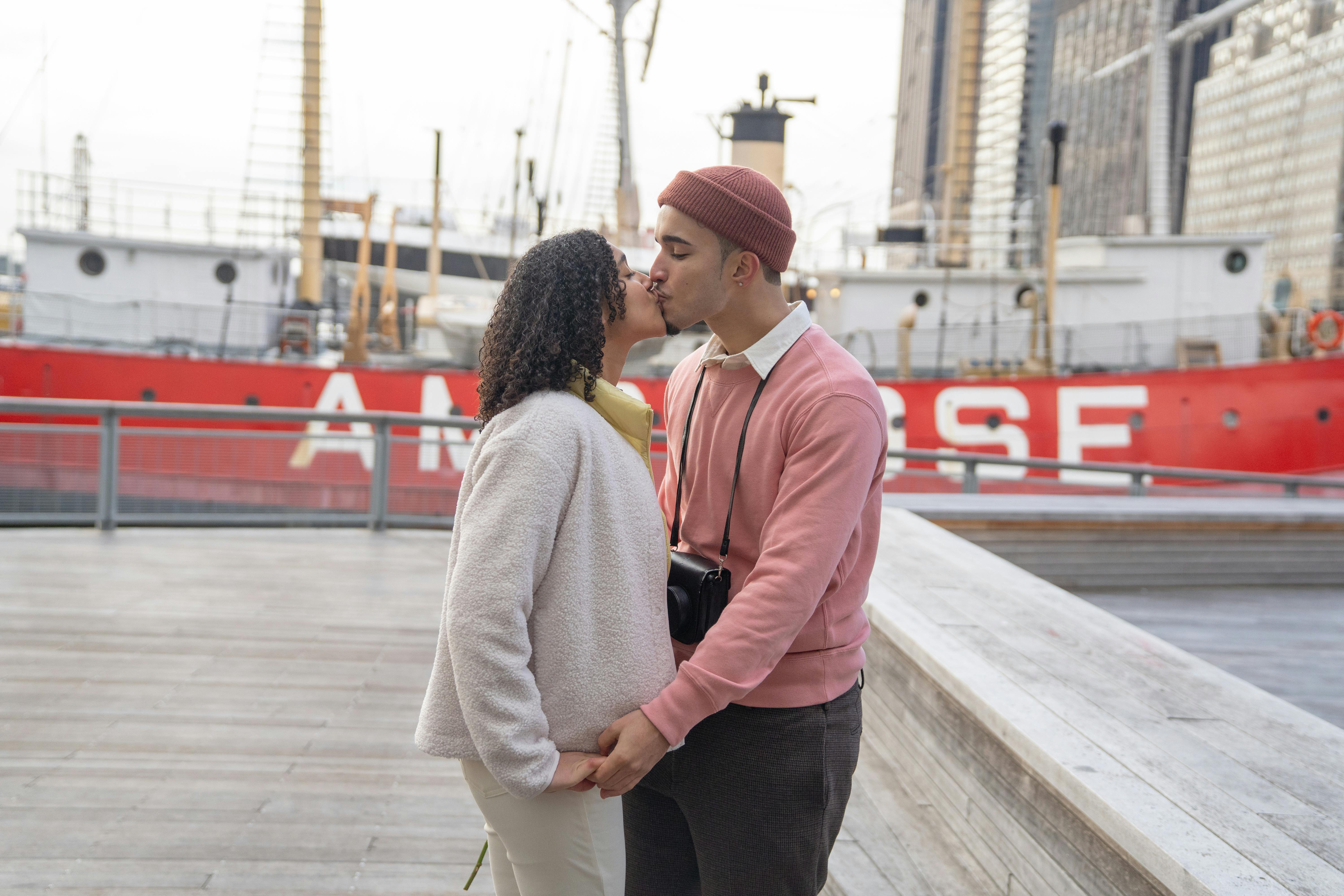 latin american couple kissing on seafront against ship