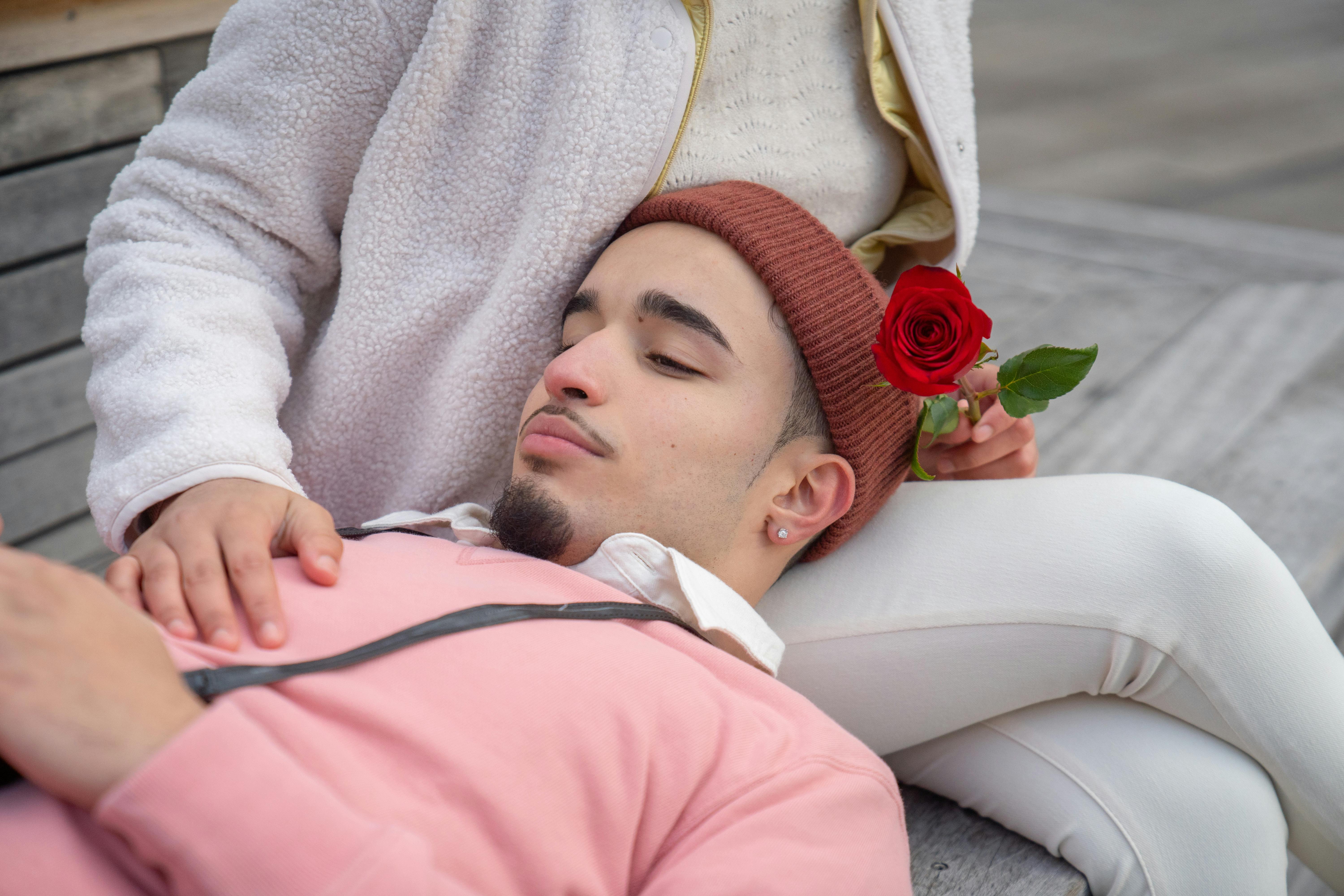 hispanic man lying on girlfriend laps on bench in street