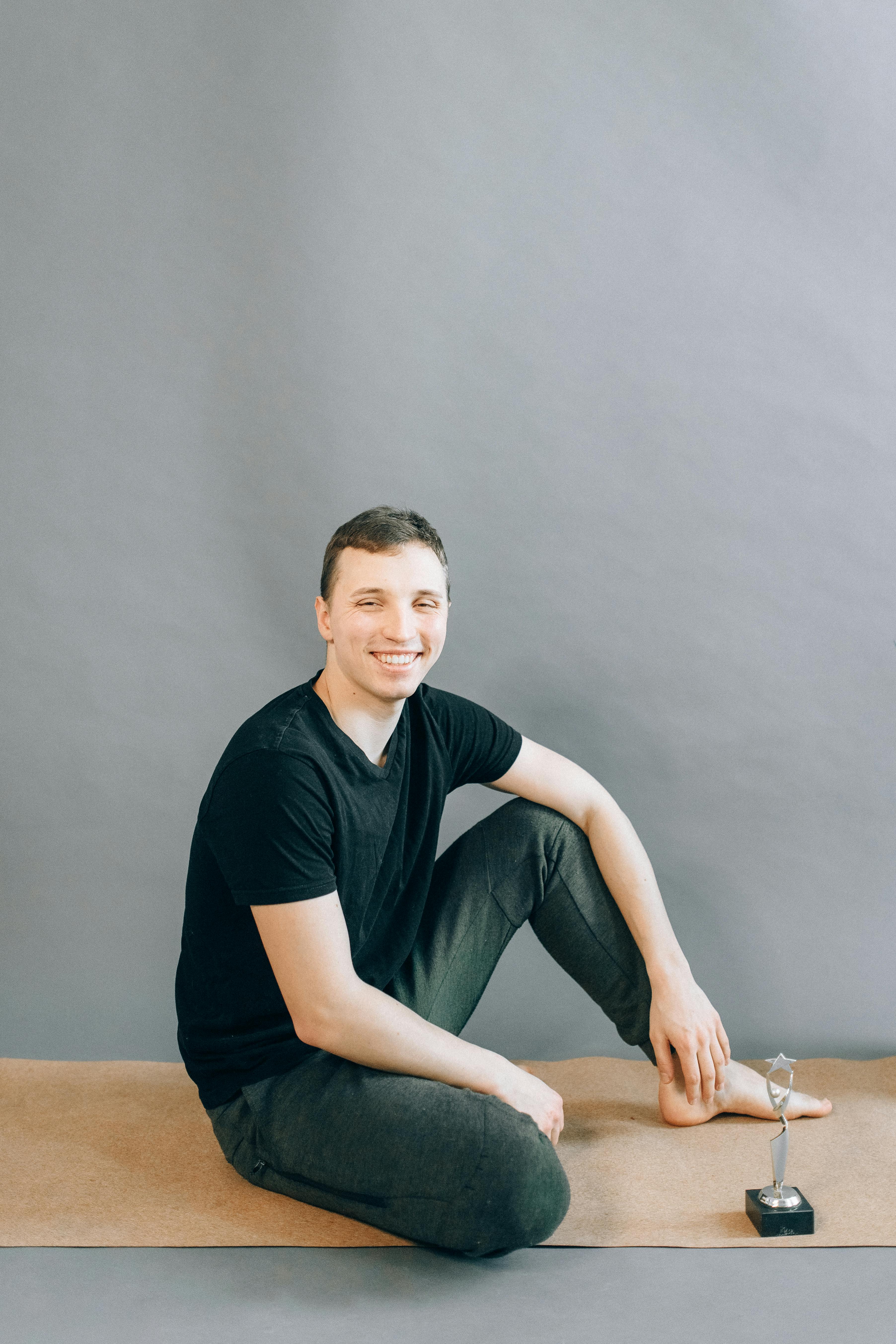 man in black crew neck t shirt and black pants sitting on brown wooden table