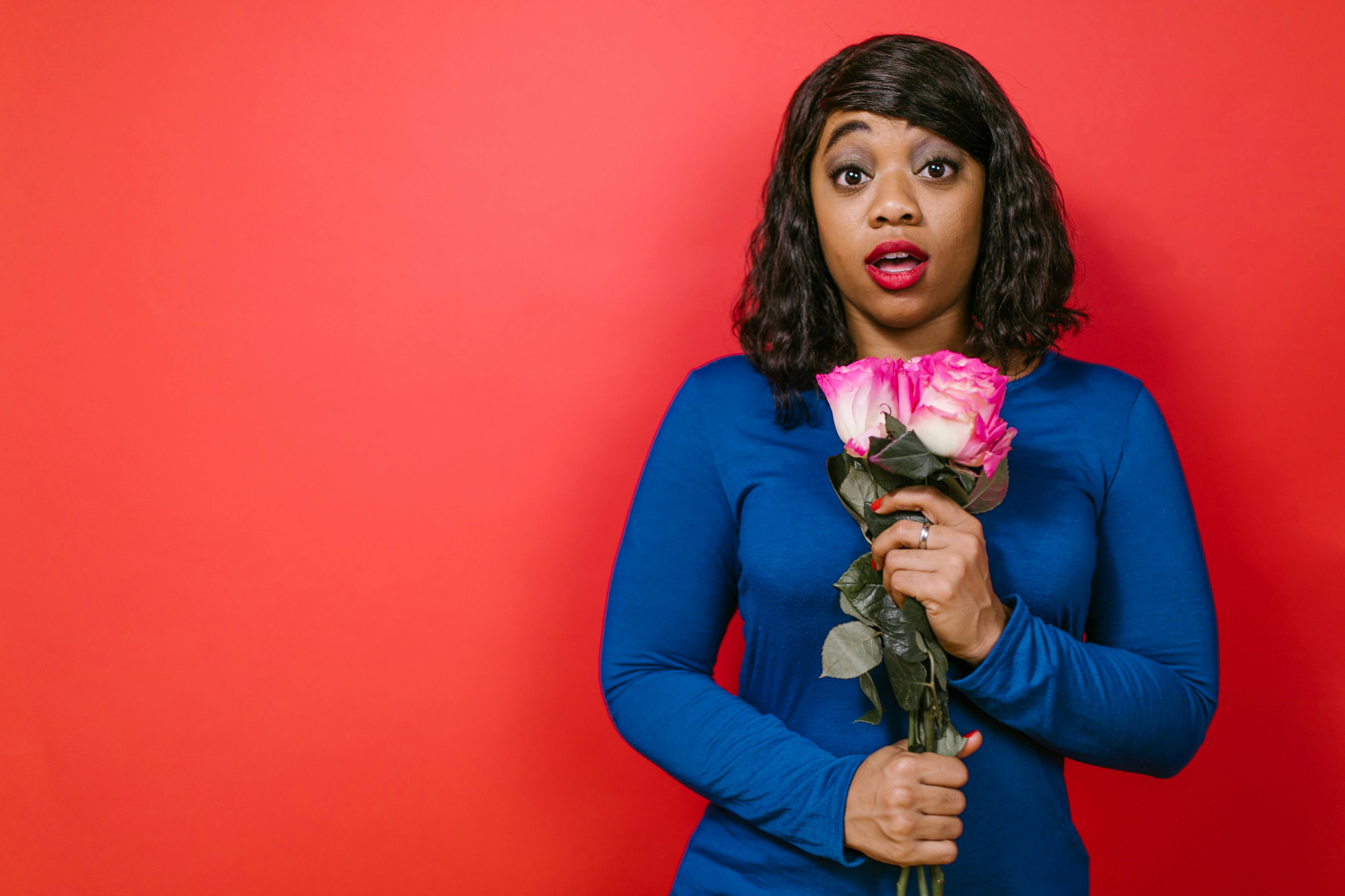 woman in blue long sleeve shirt holding pink roses