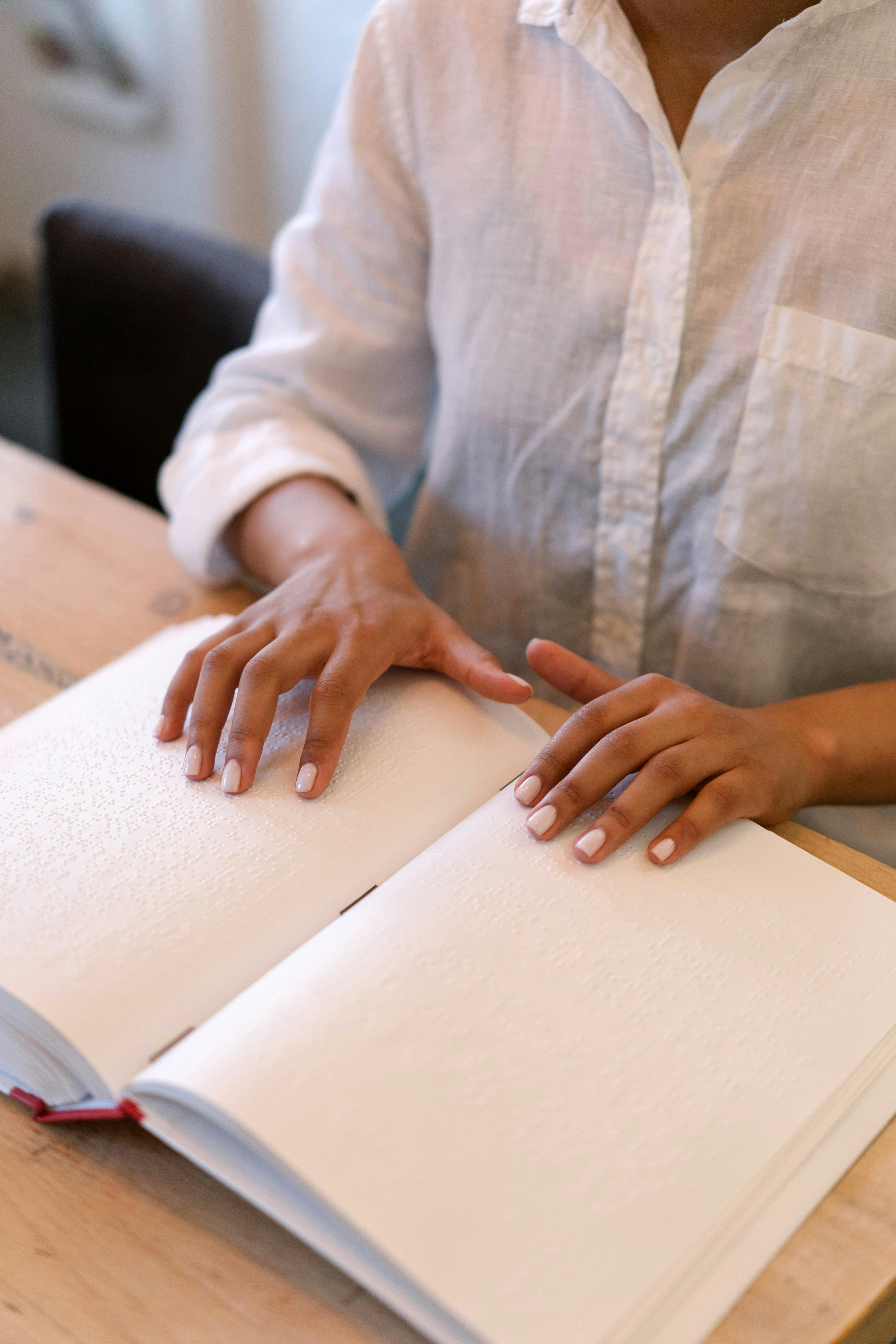 a person in white dress shirt reading a braille book