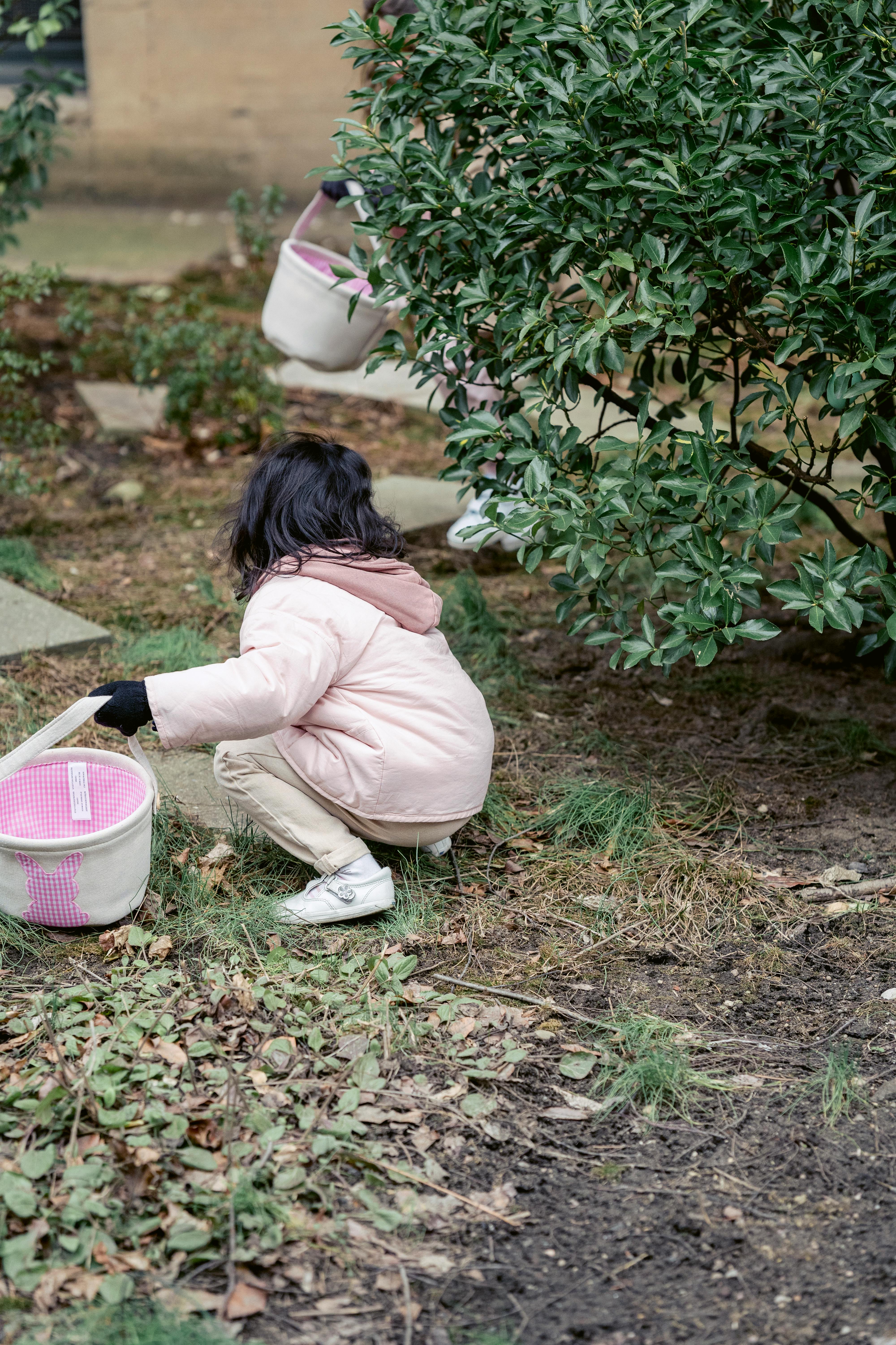faceless girl with basket hunkering in spring garden