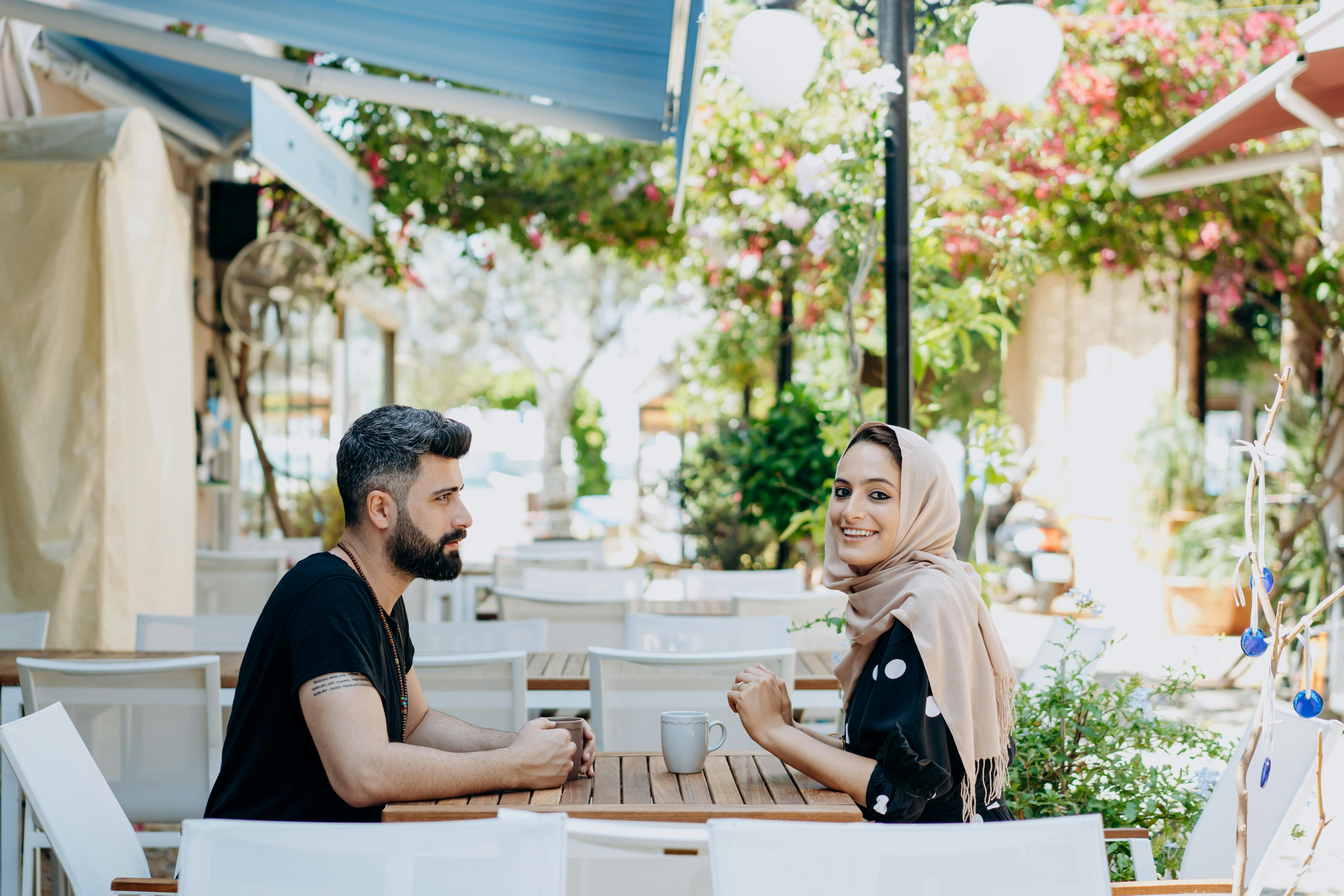 man and woman in headscarf drinking from cups outside