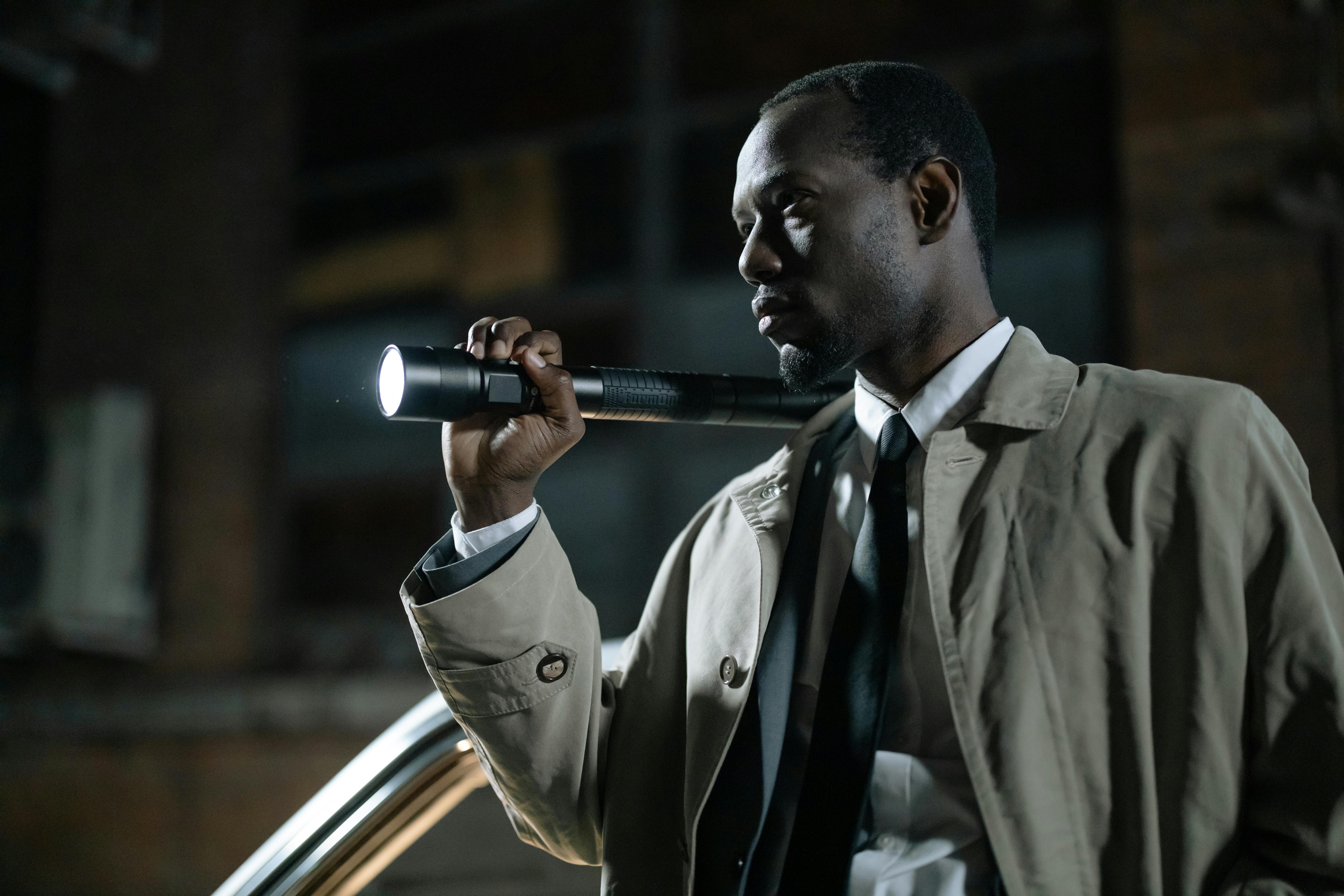 man in beige coat holding a flashlight