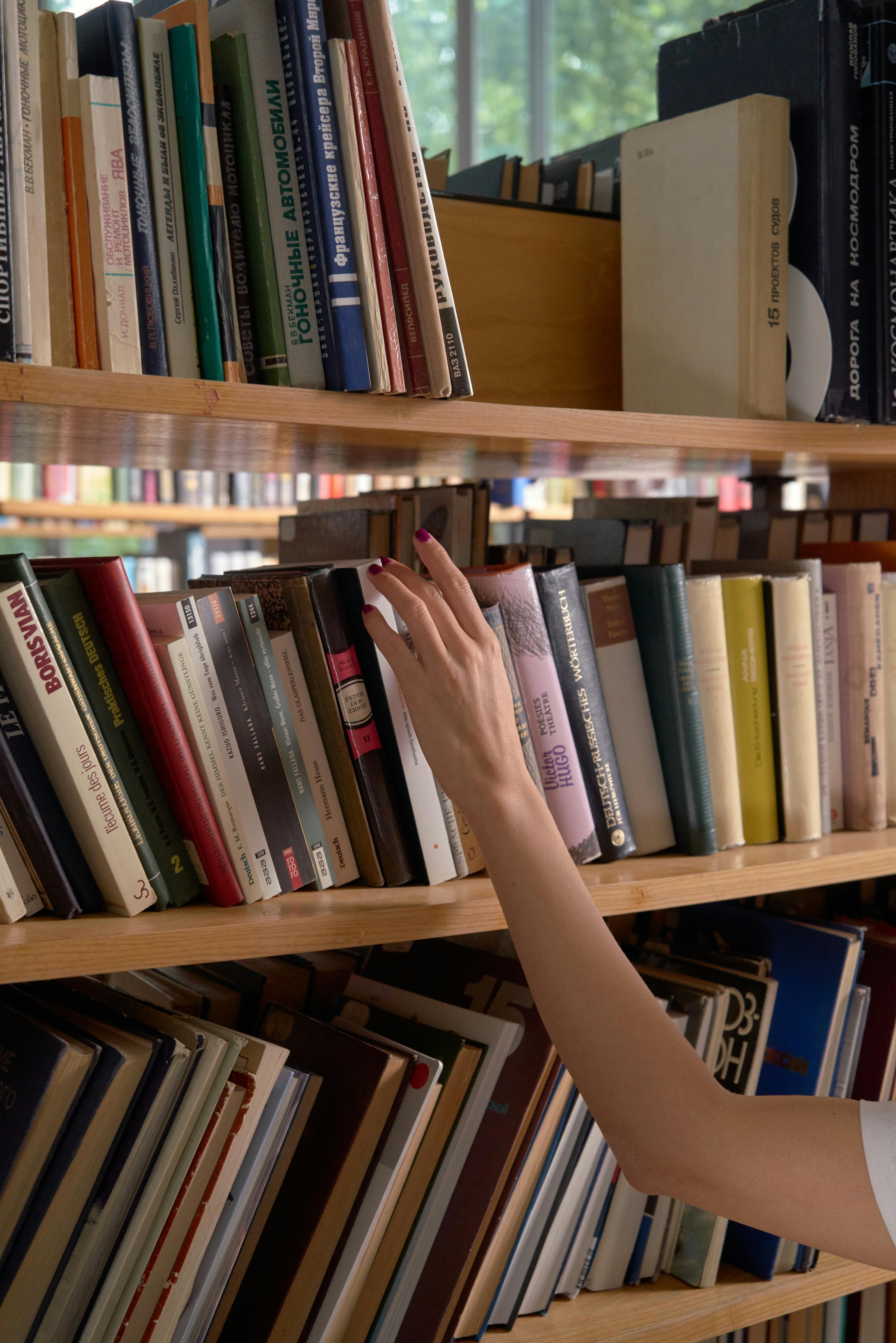 a person looking for a book on a shelf