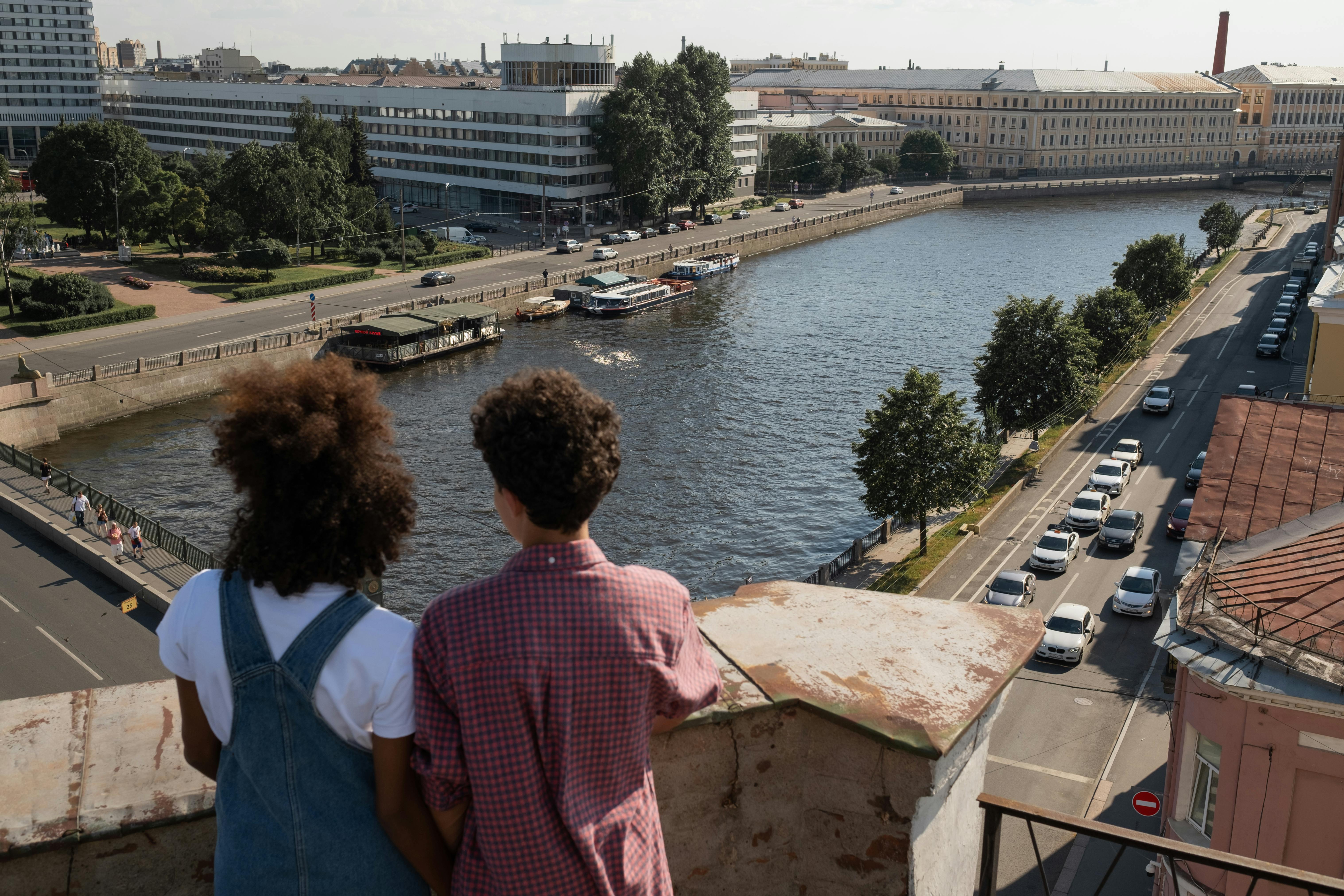 teenage couple on date standing on rooftop and admiring beautiful view at river and city